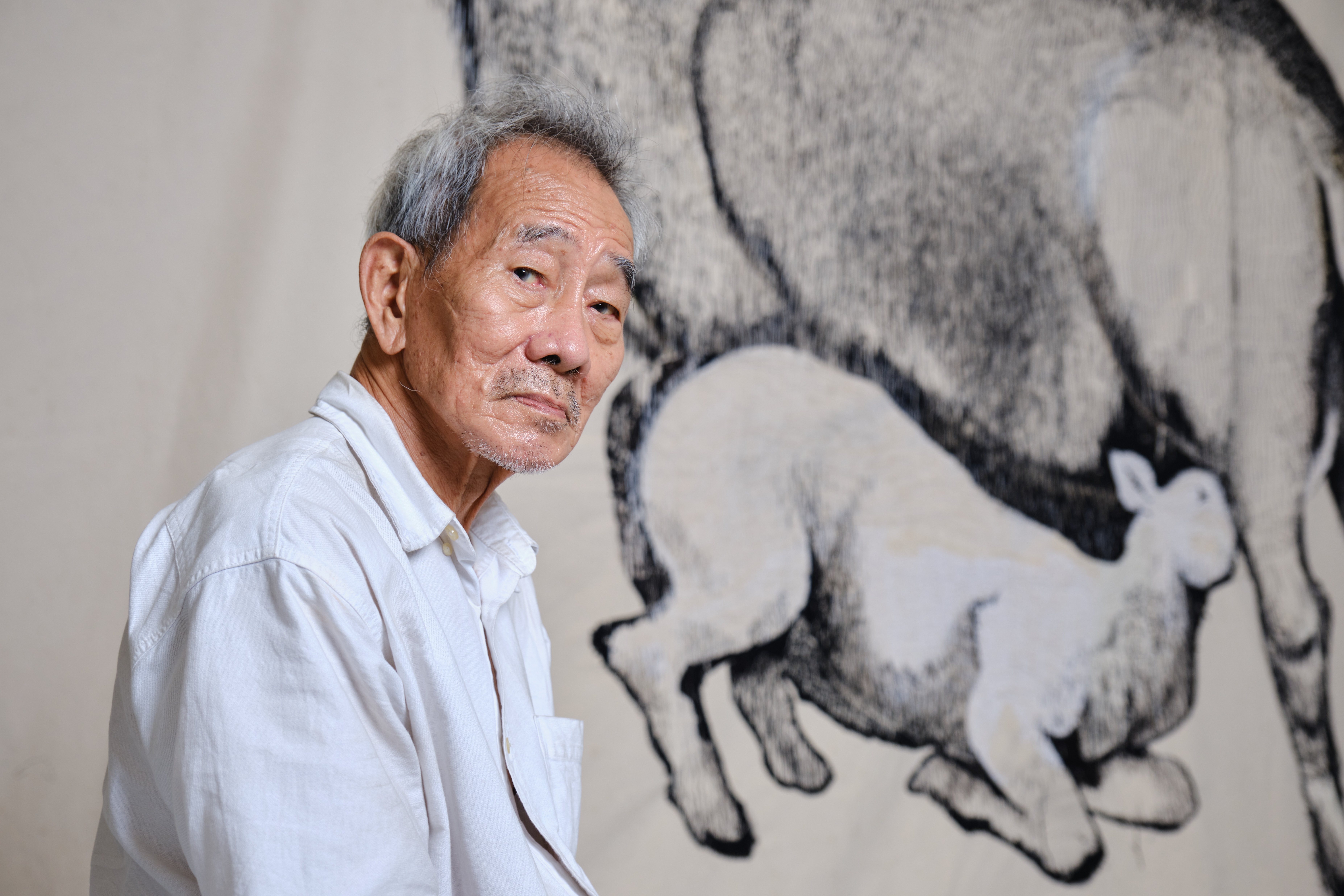 Wide shot of Tang Da Wu with an exhibition piece from Our Children