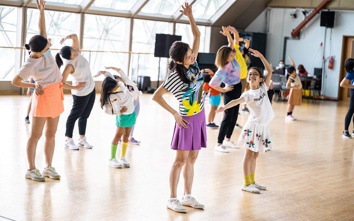 Wide shot of adults and children participating in a ballet workshop