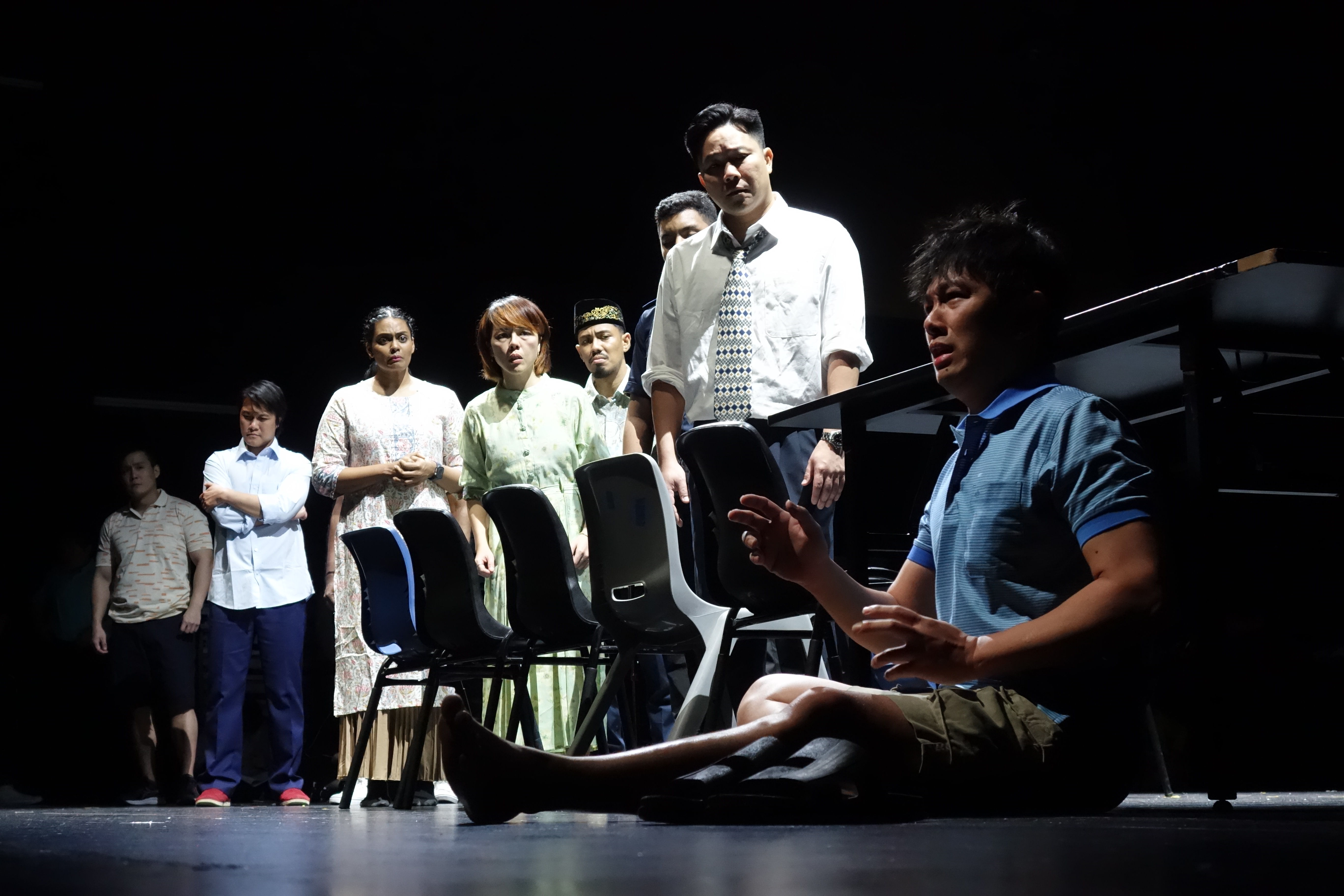 Wide shot of the cast listening to Seng Huat describing his trauma 