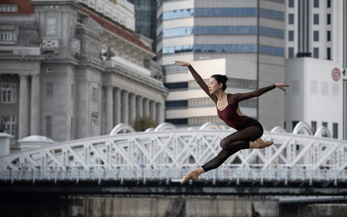 Wide shot of a dancer leaping against a backdrop of the Cavenagh Bridge