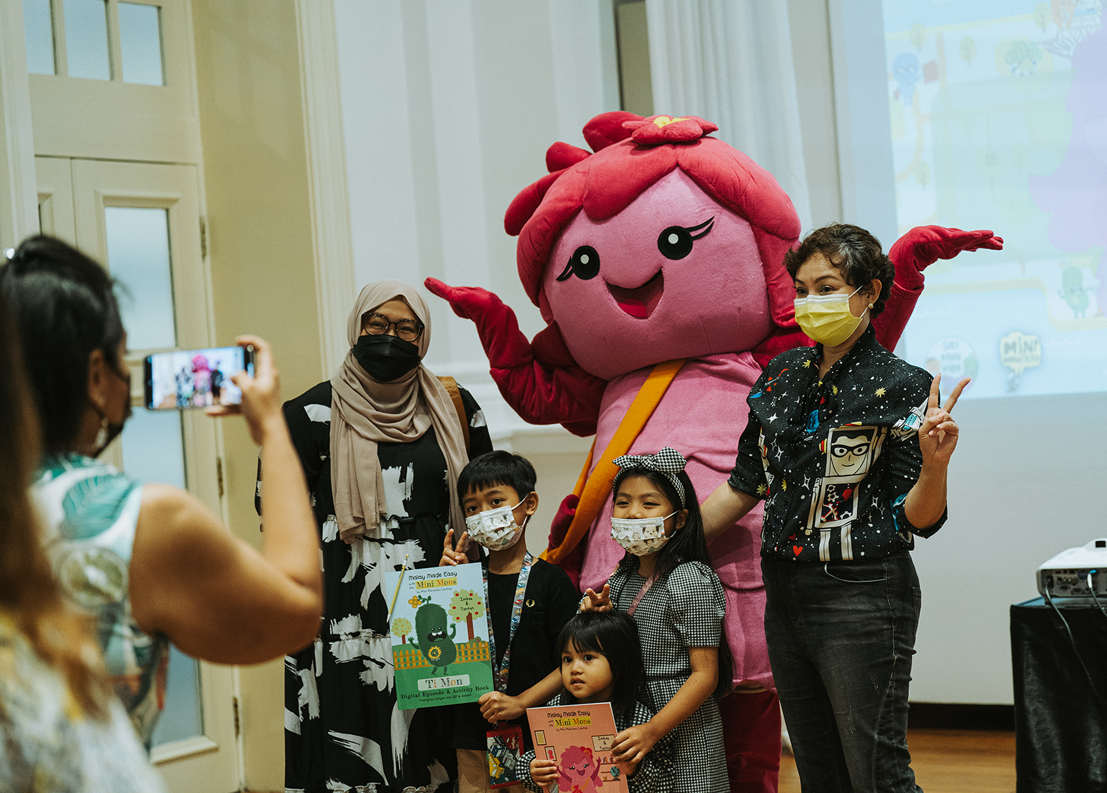  Wide shot of kids and adults alike taking a shot with a mascot from Monstrous Fun