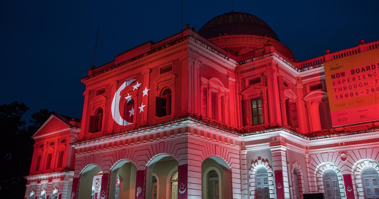 Wide shot of the Singapore flag projected on the facade of the National Museum of Singapore building