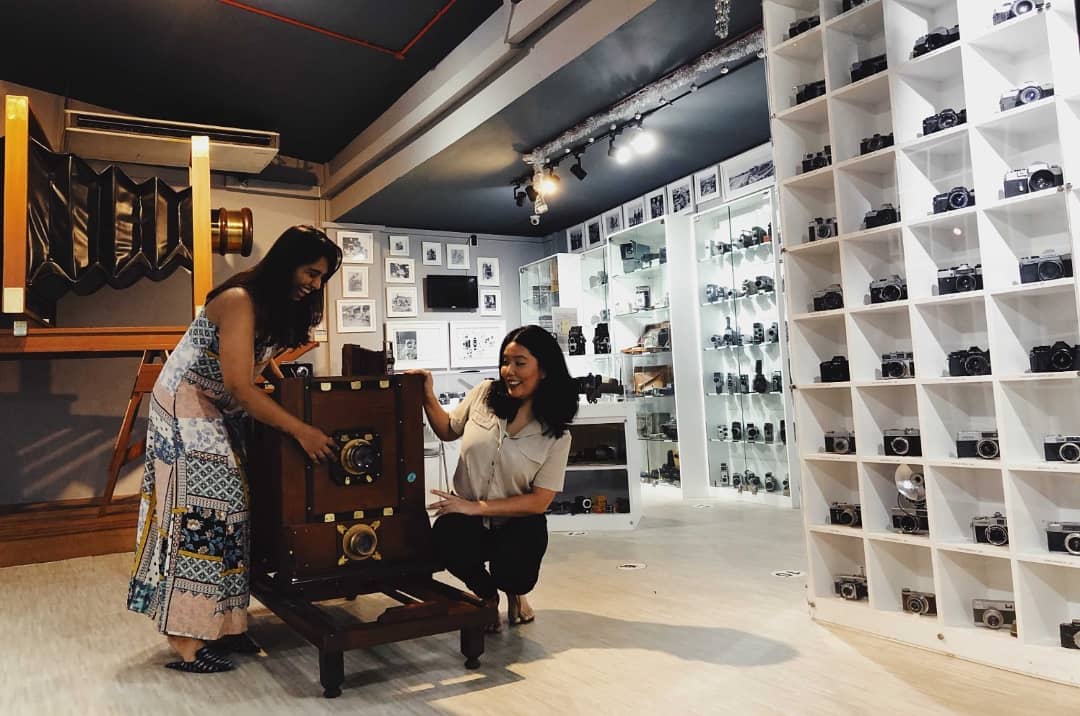  Wide shot of two women interacting with a large camera exhibition piece