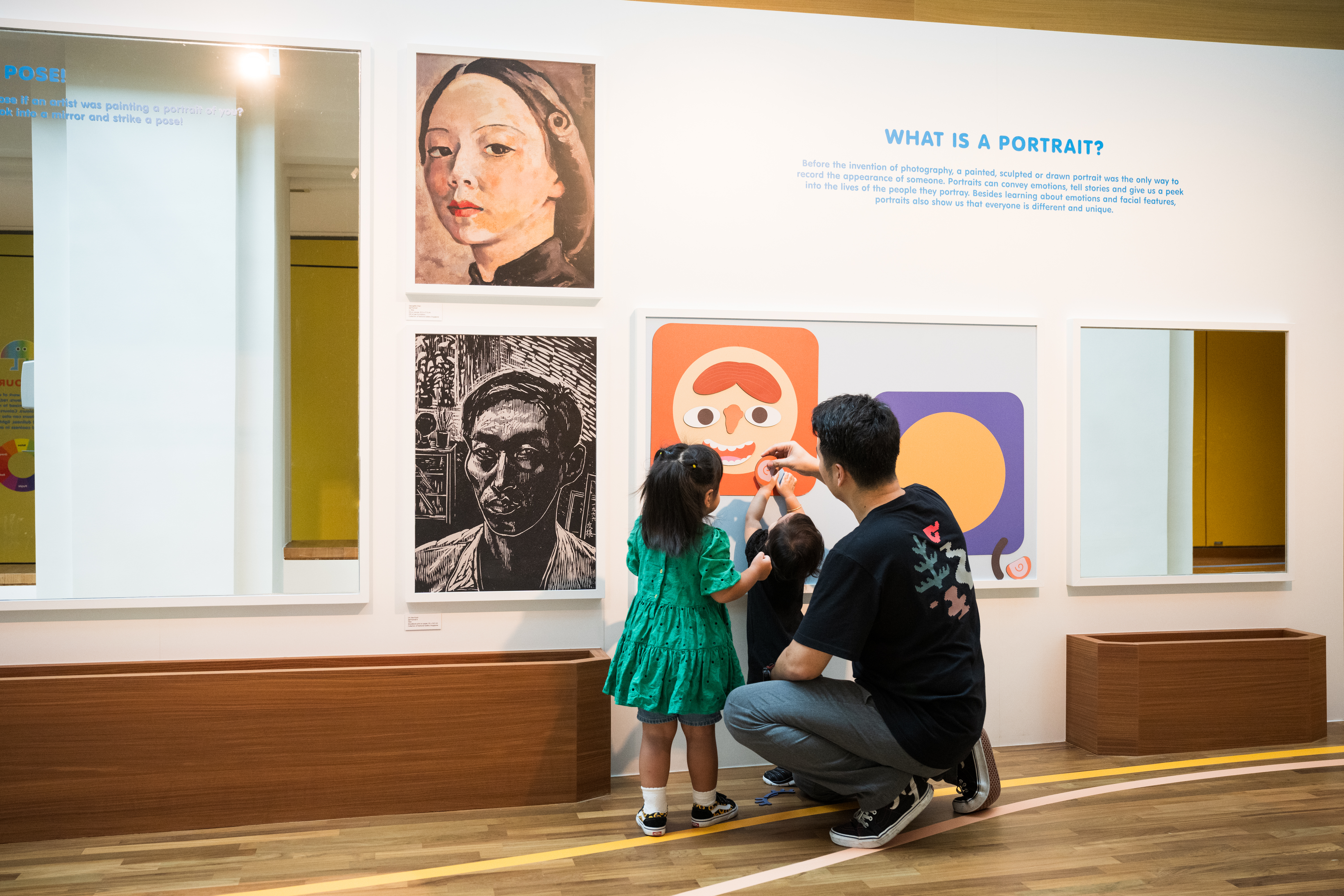 Wide shot of a man and two children interacting with the exhibition space in the Portrait Gallery