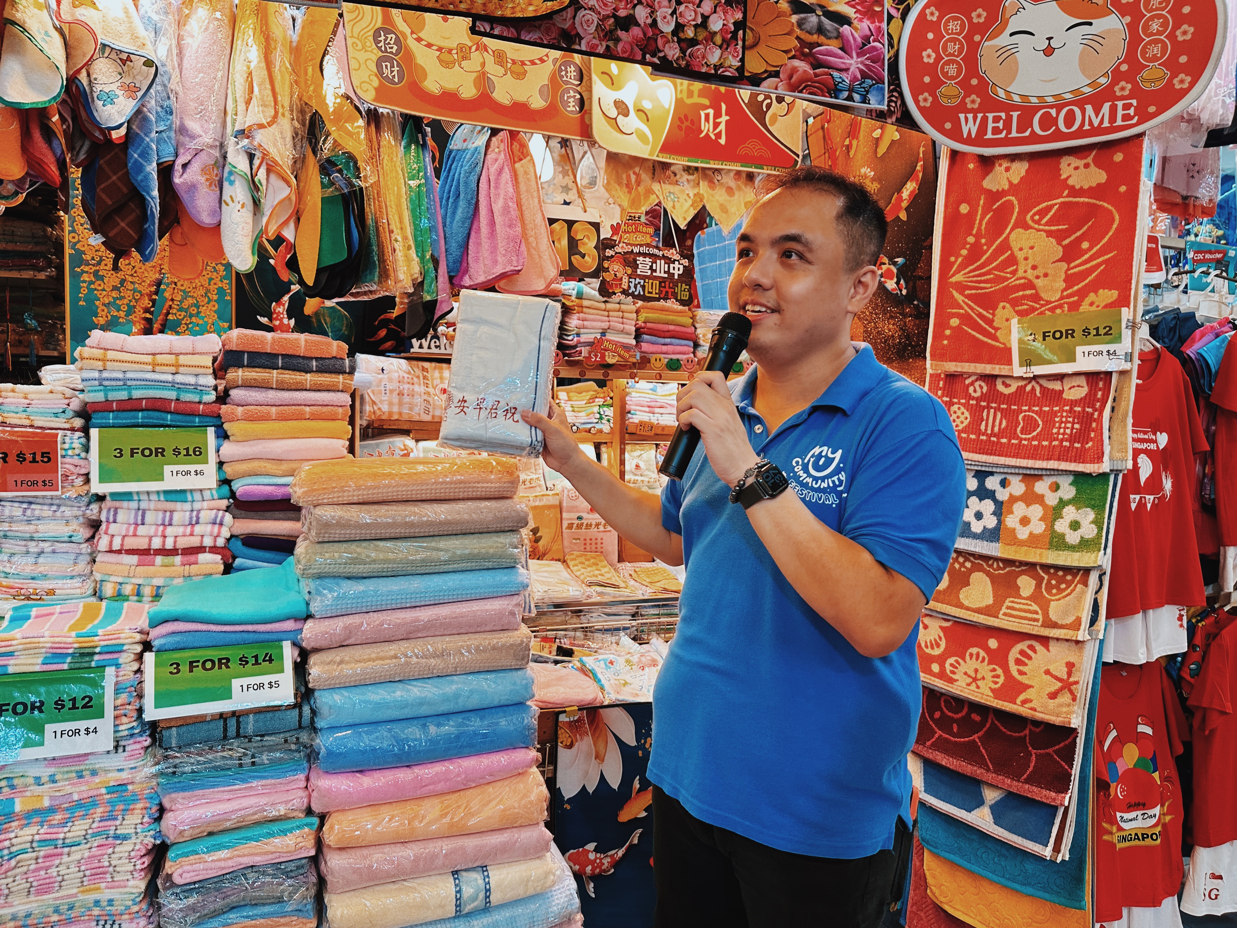 Wide shot of festival director Kwek Li Yong speaking in front of a towel shop