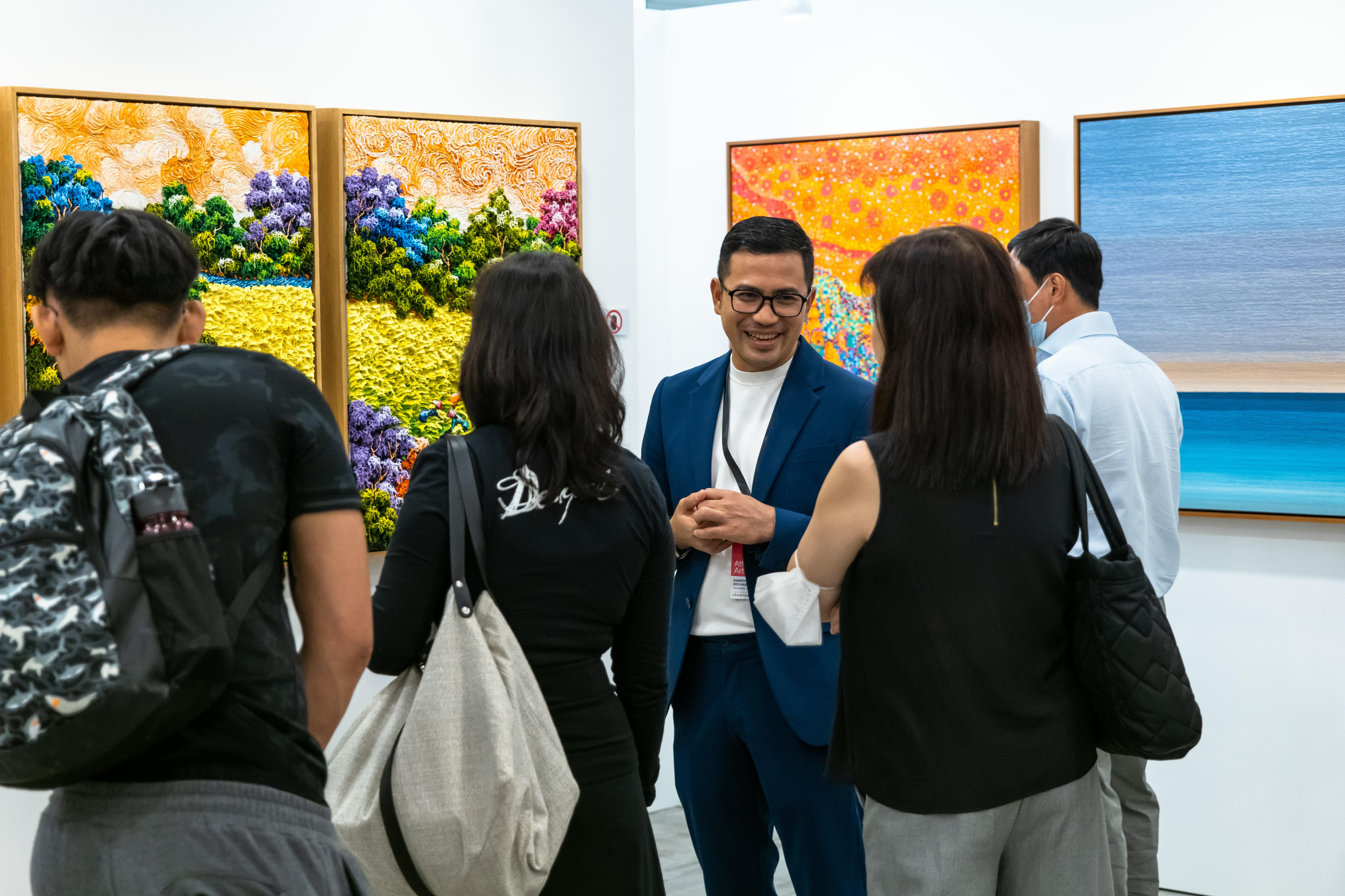 Mid shot of a curator speaking to fair-goers about the artwork