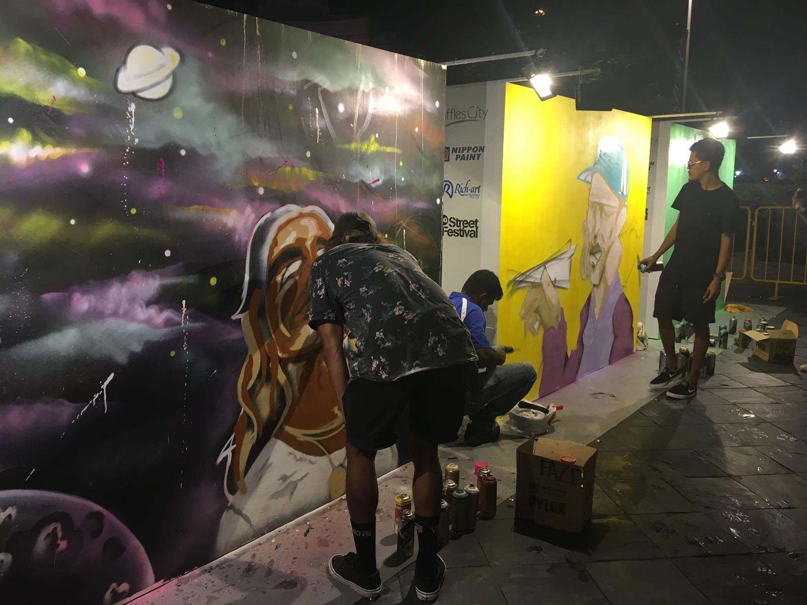 Wide shot of artists working on a wall mural with spray paint