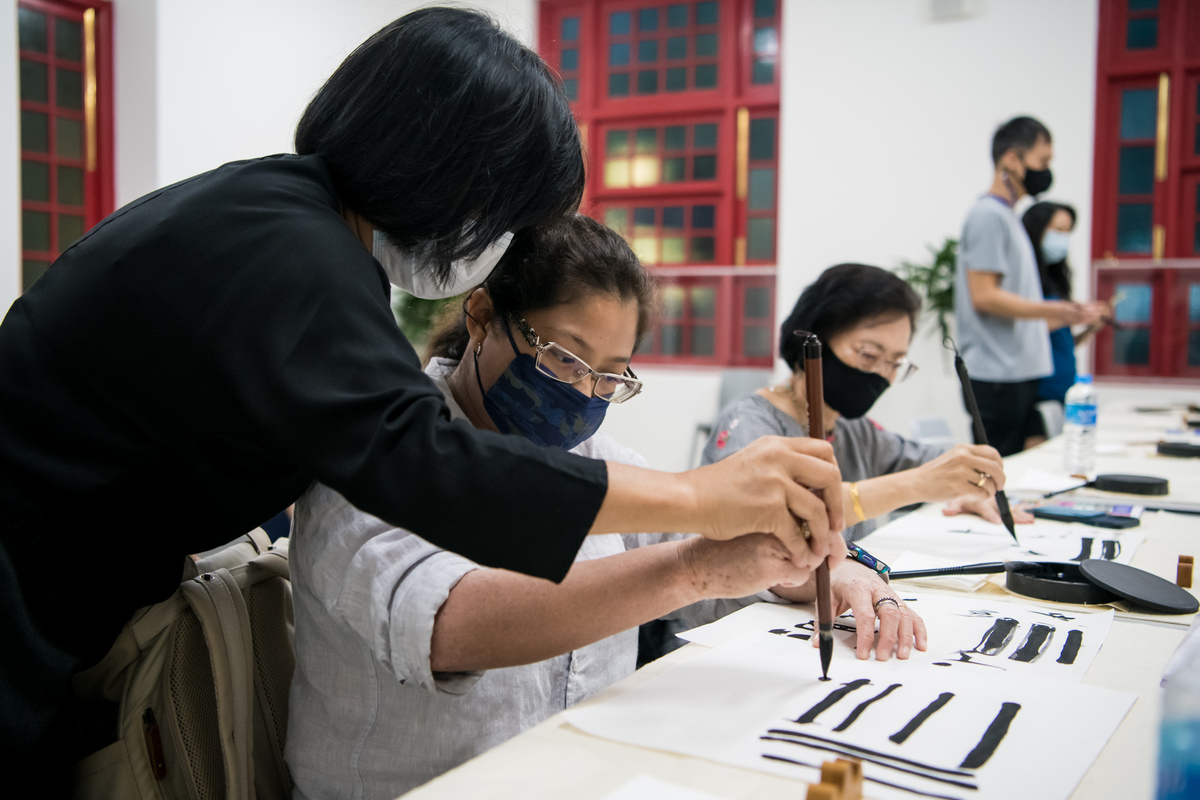 Close up of a woman guiding a participant during a calligraphy workshop