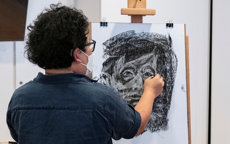   Mid-shot of a man doing a self-portrait on canvas