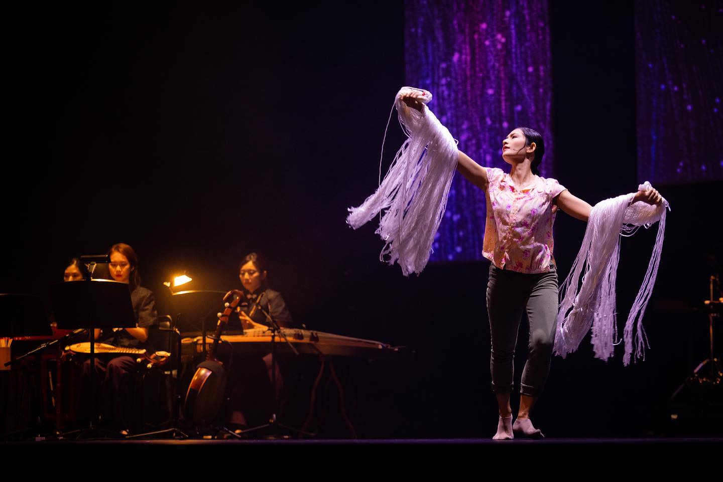 Wide shot of a performer in the foreground backed up by musicians in the background