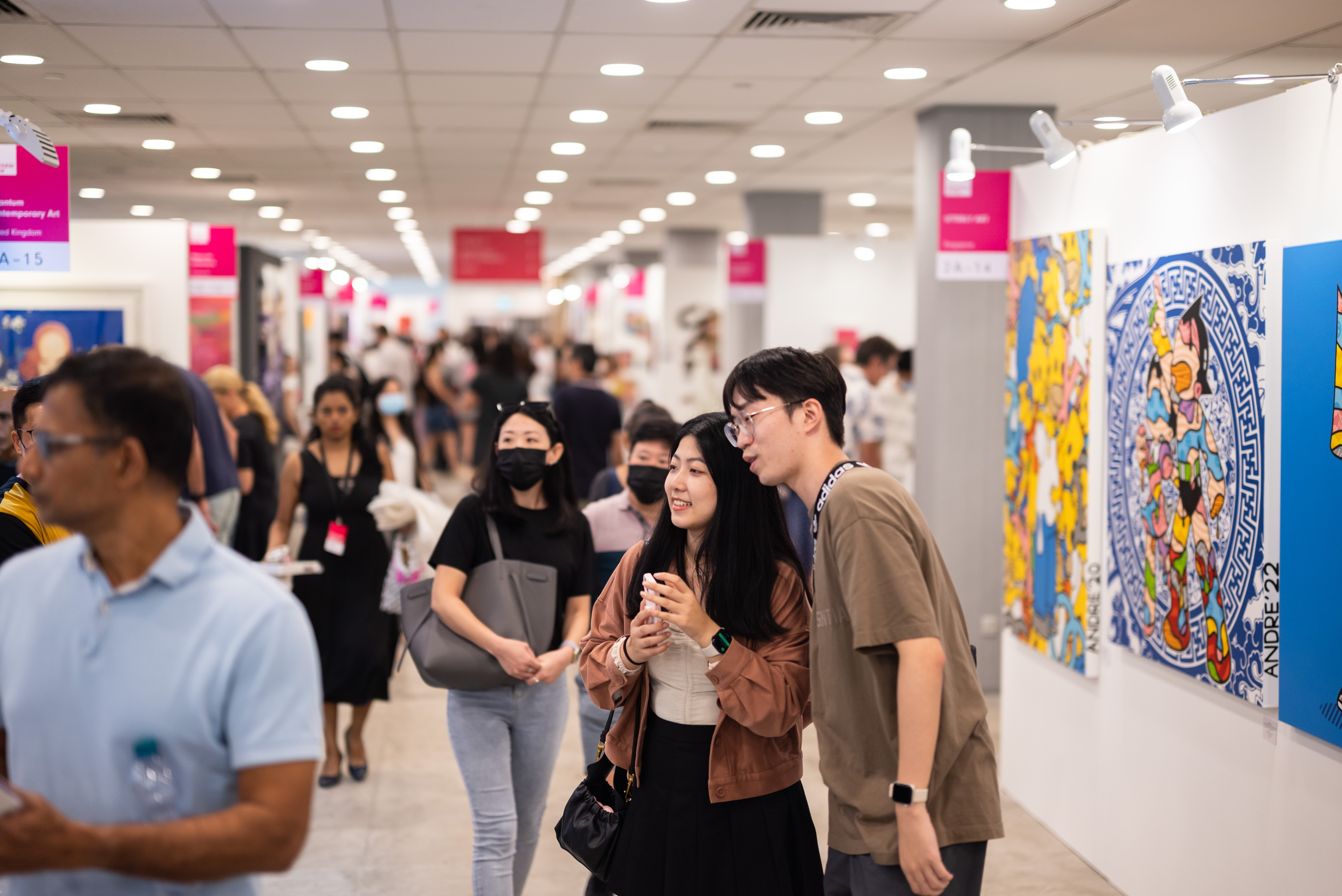 Wide shot of the Affordable Art Fair 2022 focusing on a couple admiring the artwork. 