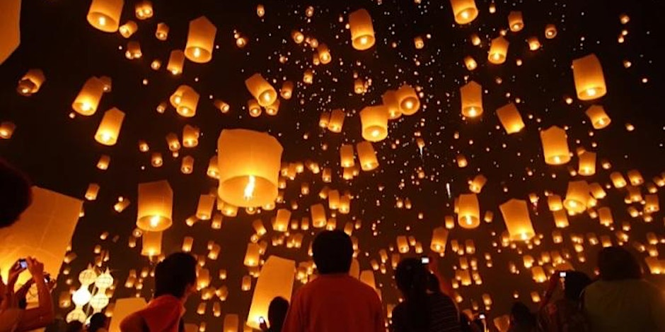 Mid shot of a crowd of people admiring a sky full of lanterns