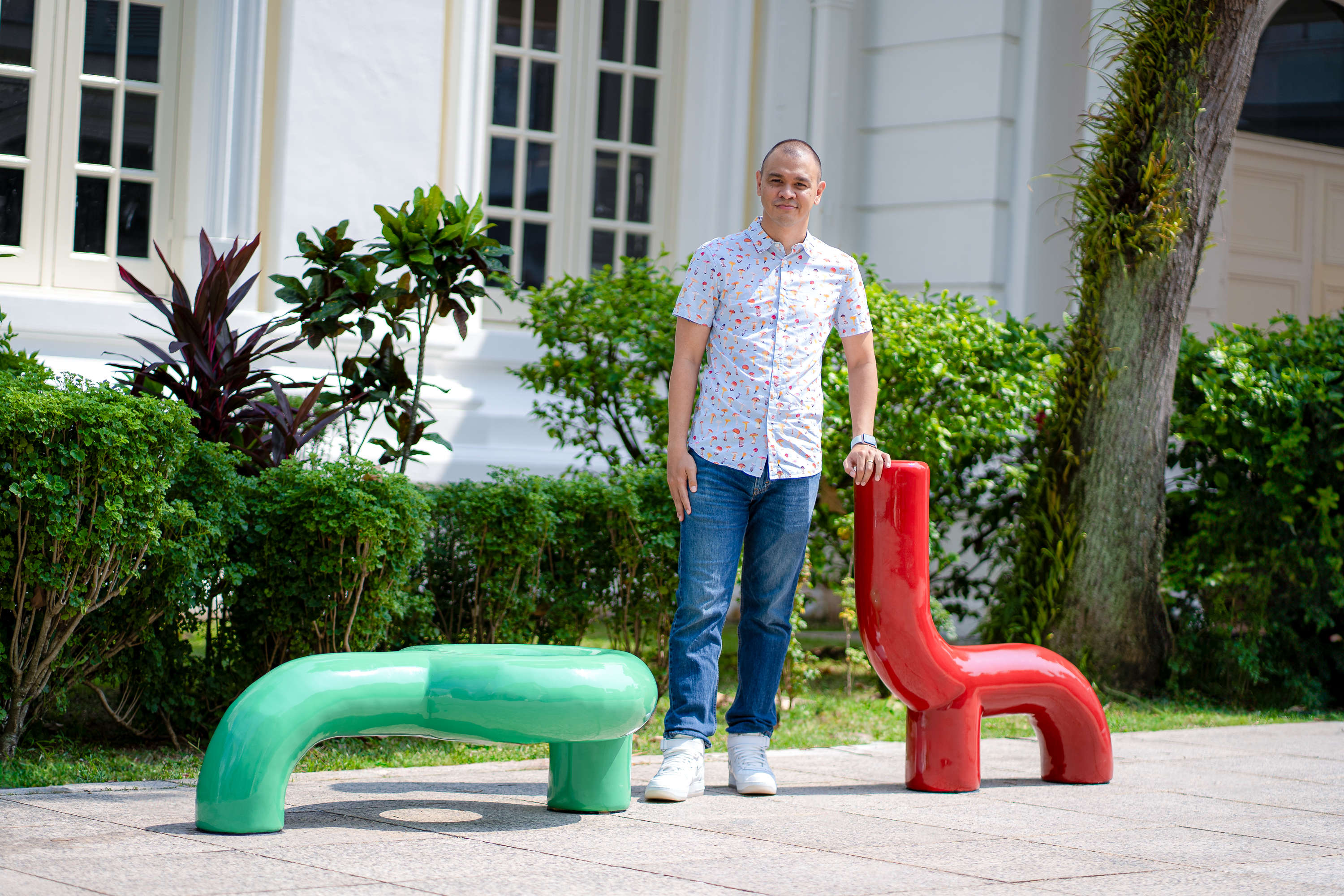 Wide shot of Wesley Lee Aroozoo posing with artwork This Is Not A Bench