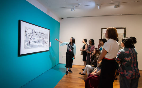 Wide shot of a curator introducing an exhibition to guests