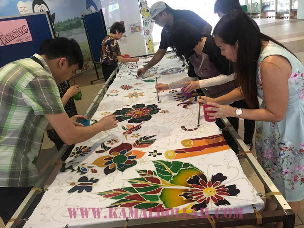 Mid shot of a group of people working on a Batik painting